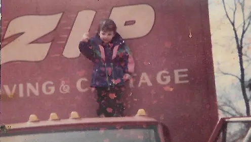 vintage scanned photo of child on top of a-zip moving truck