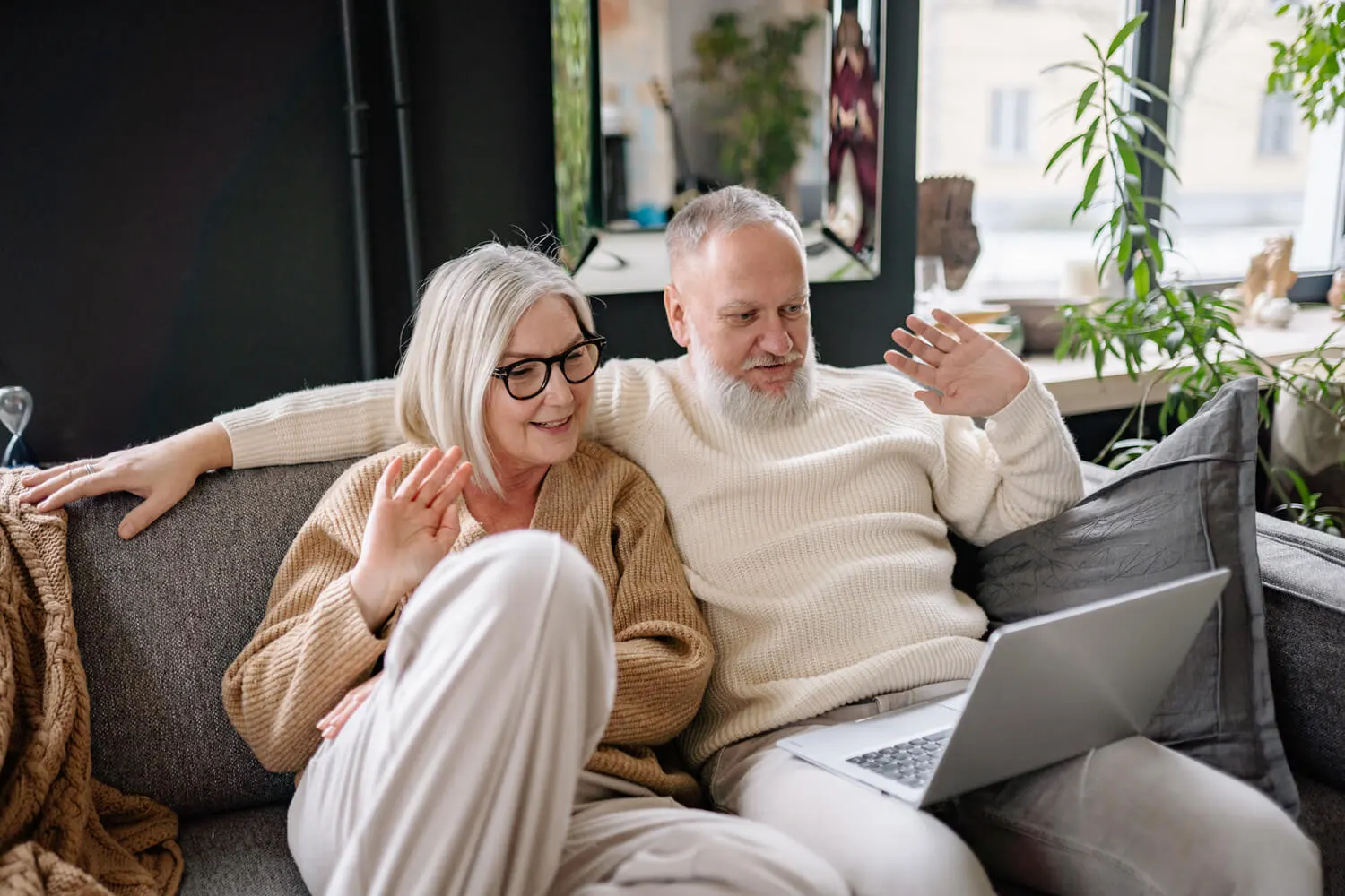 A senior couple using a laptop on the couch